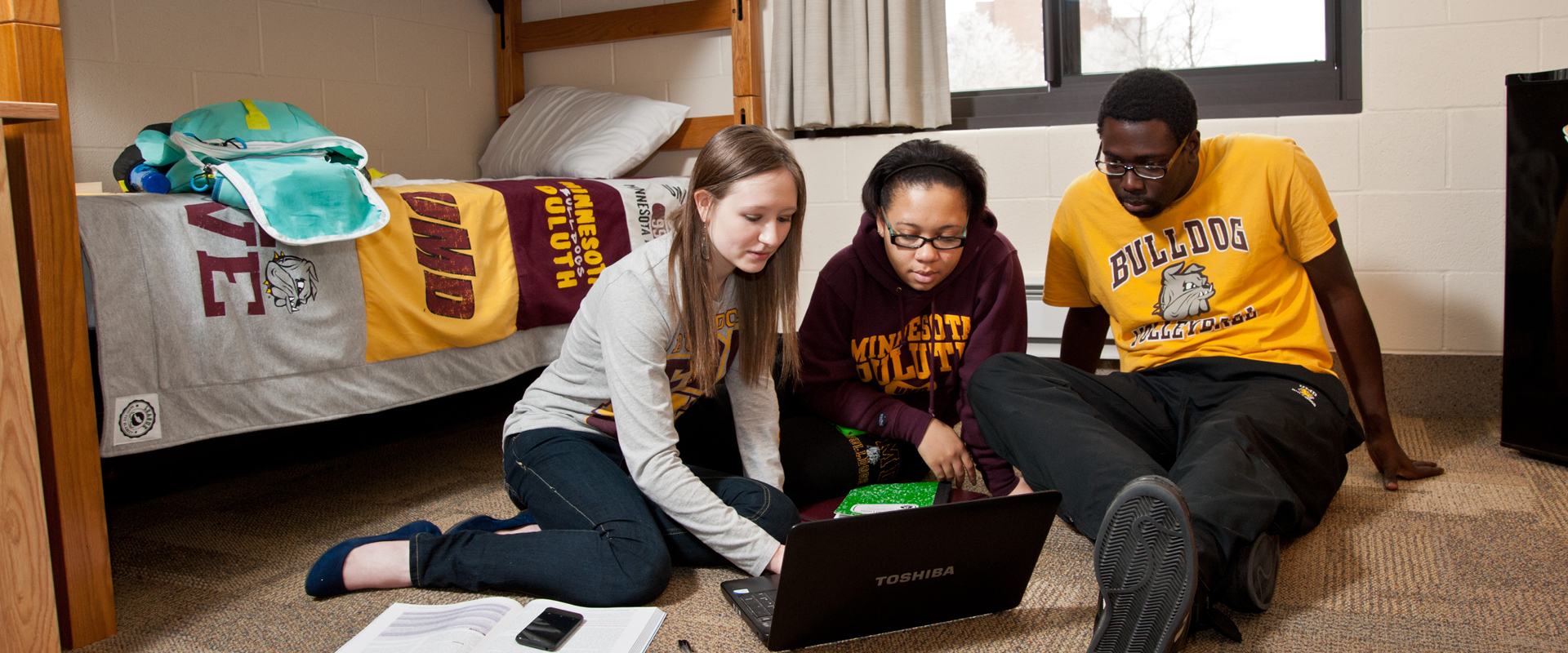 Students gathered in a dorm room doing homework